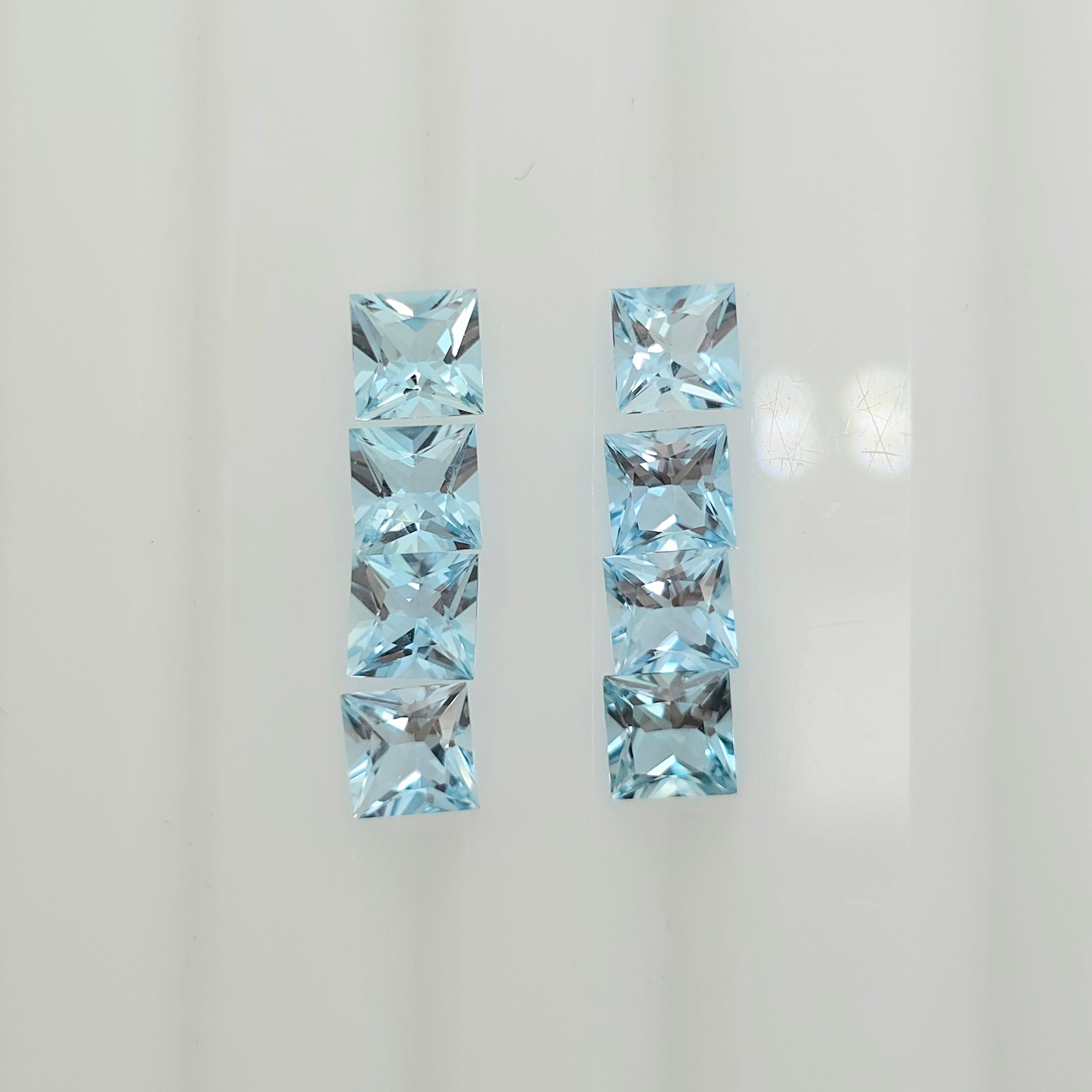 Eight square faceted light blue gemstones arranged in two vertical columns against a plain white background