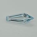 A single faceted light blue gemstone with an elongated kite shape, shown on a neutral light gray background.