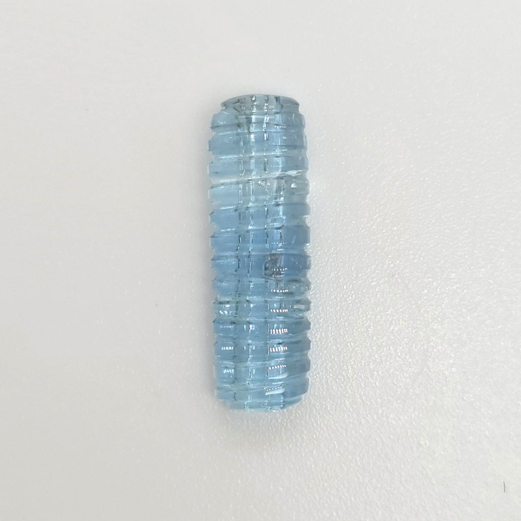 A light blue ribbed gemstone shown vertically on a plain white background.