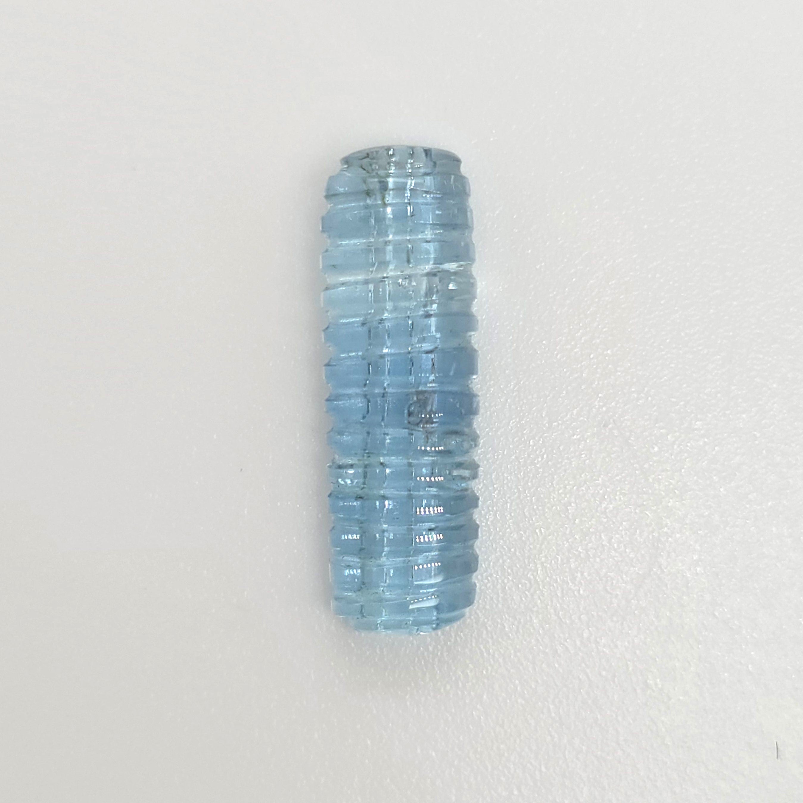 A light blue ribbed gemstone shown vertically on a plain white background.