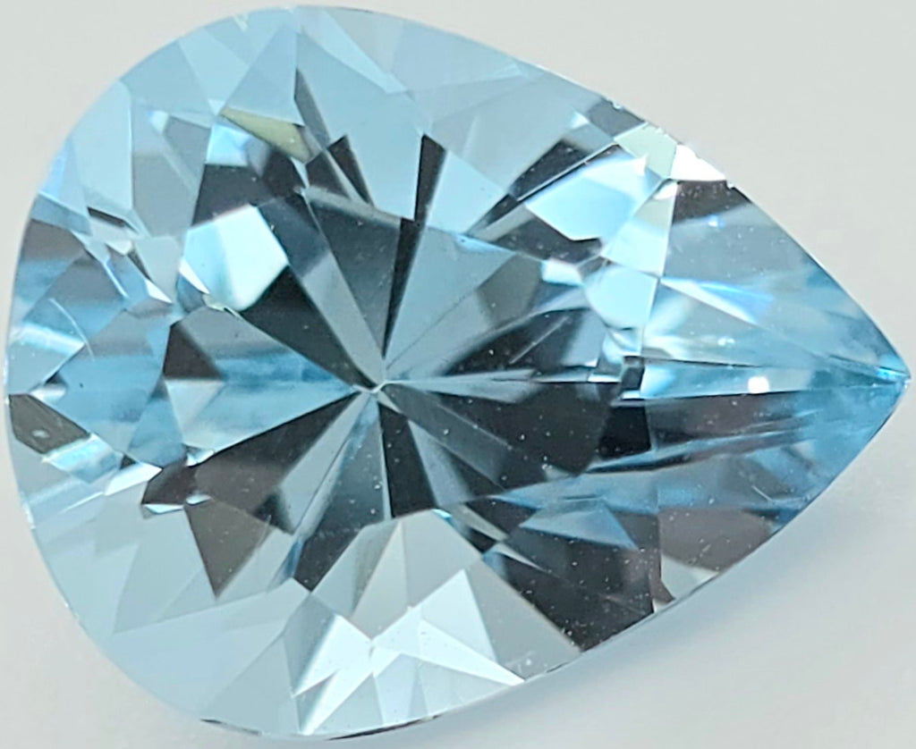 A single pear-cut light blue gemstone with brilliant faceting, shown in close-up on a plain light background.
