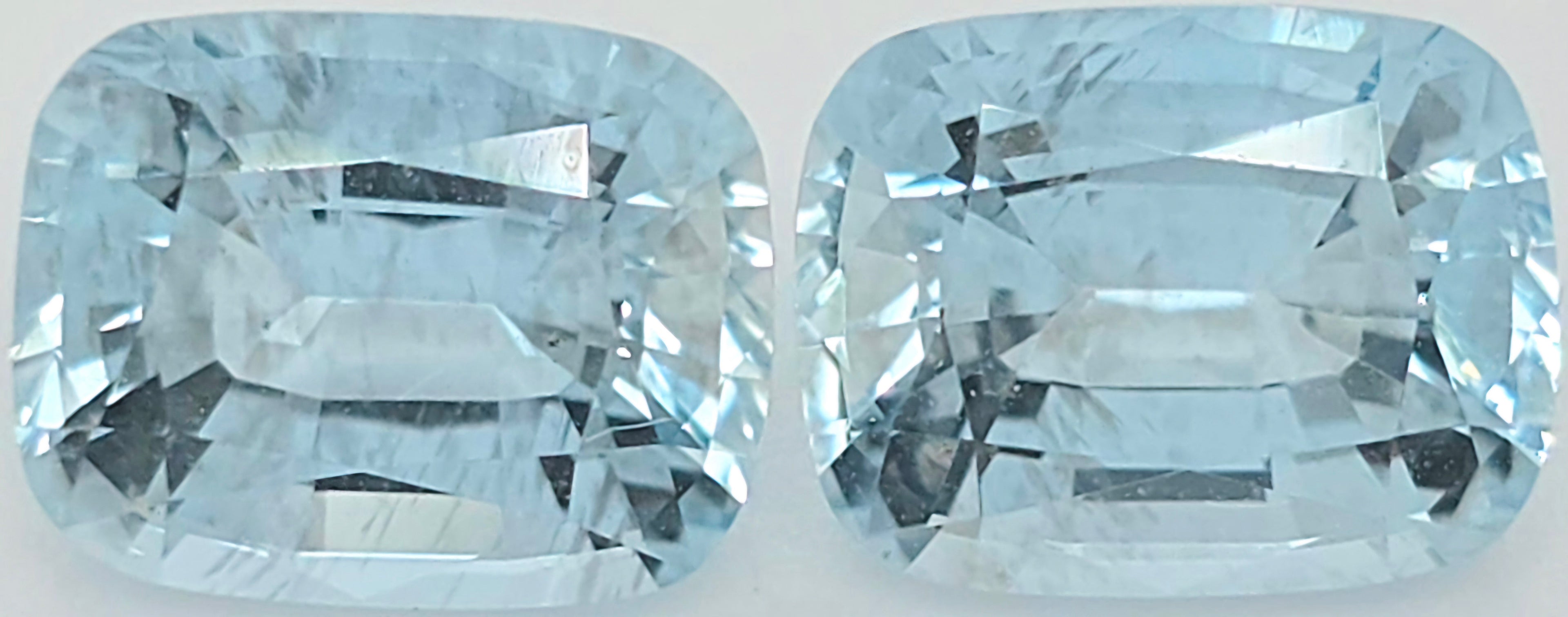 Two light blue cushion-cut gemstones shown side by side on a plain white background.