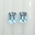 Two cushion-cut light blue gemstones displayed side by side on a clean white background.