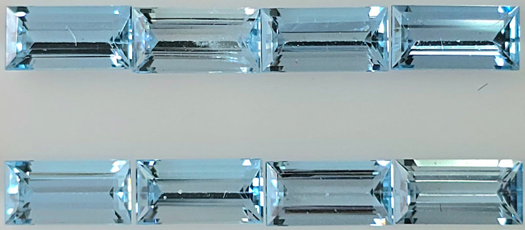 Eight rectangular light blue baguette cut gemstones arranged in two rows on a plain light background.