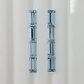 Eight baguette cut faceted light blue gemstones in two columns shown vertically on a plain light background.