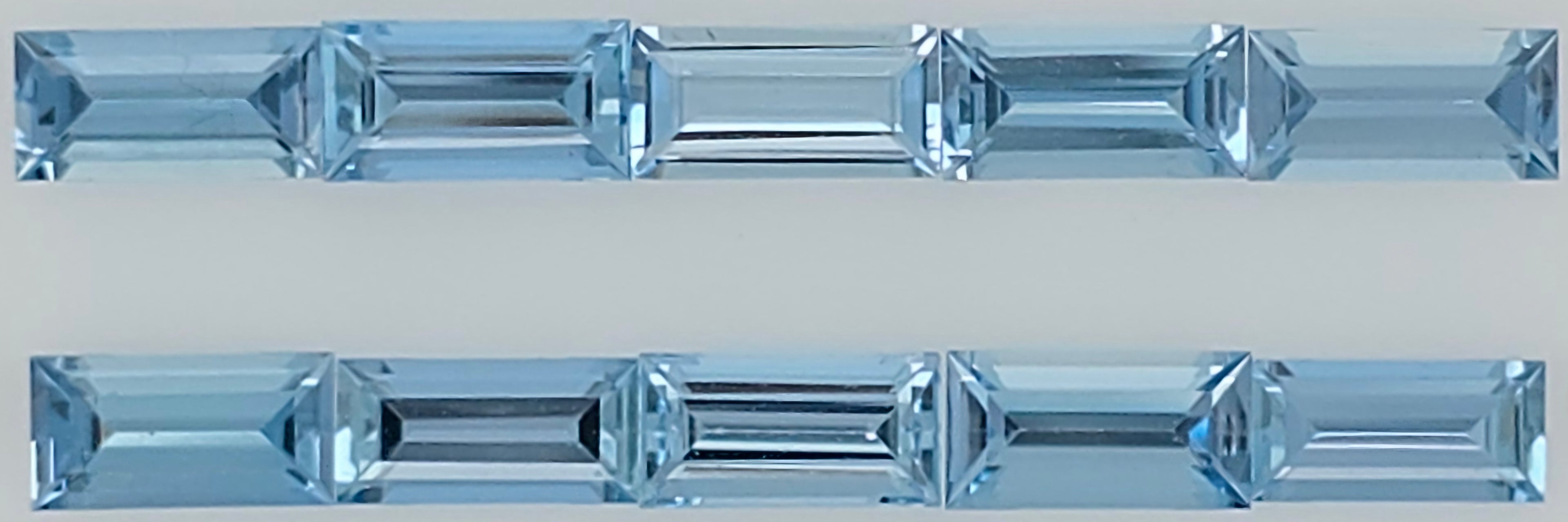 Two horizontal rows of faceted light blue rectangular gemstones shown on a plain light gray background.