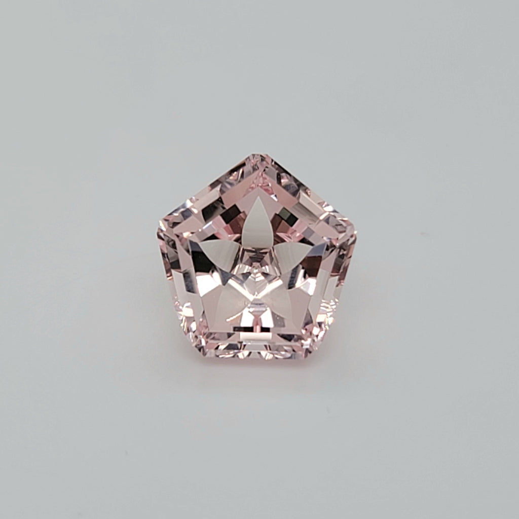 Pentagonal faceted gemstone with flower pattern on a lain white background