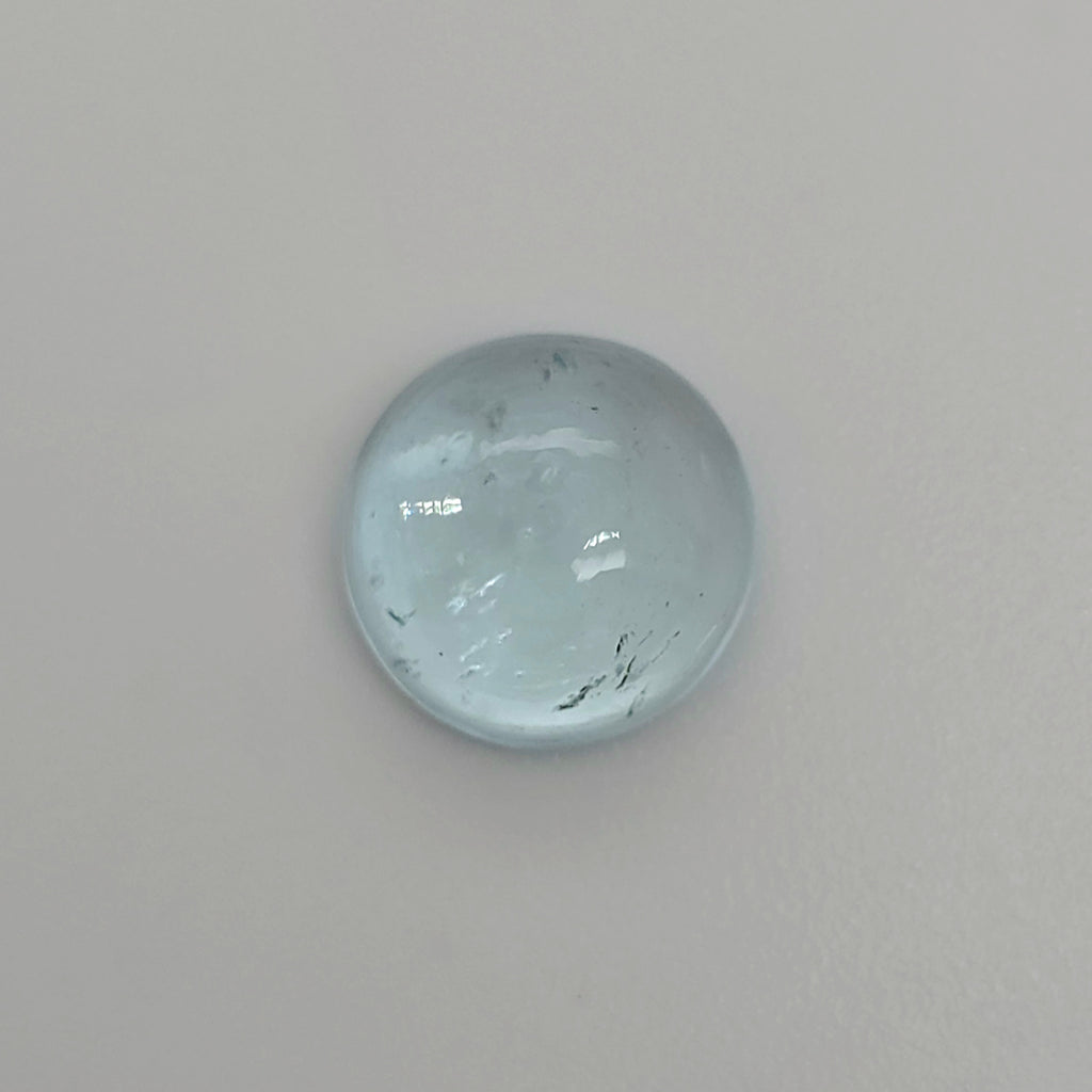 Round light blue domed gemstone against a light background