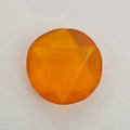 A single faceted orange gemstone with a circular shape and triangular cut facets, photographed on a plain light background.
