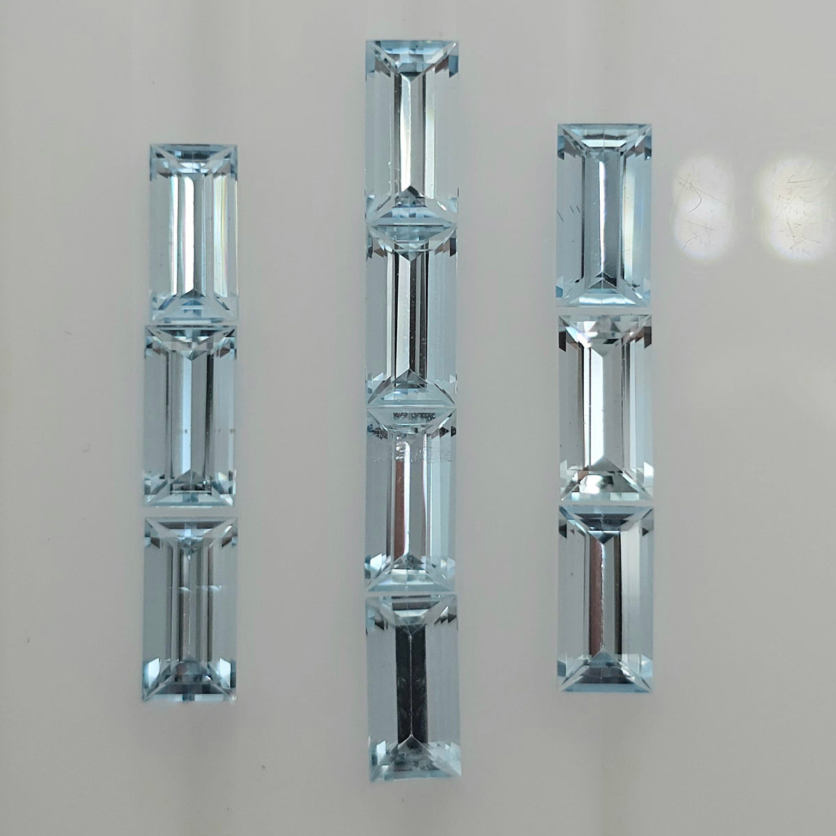 Ten light blue faceted rectangle gemstones arranged into three columns against a white background