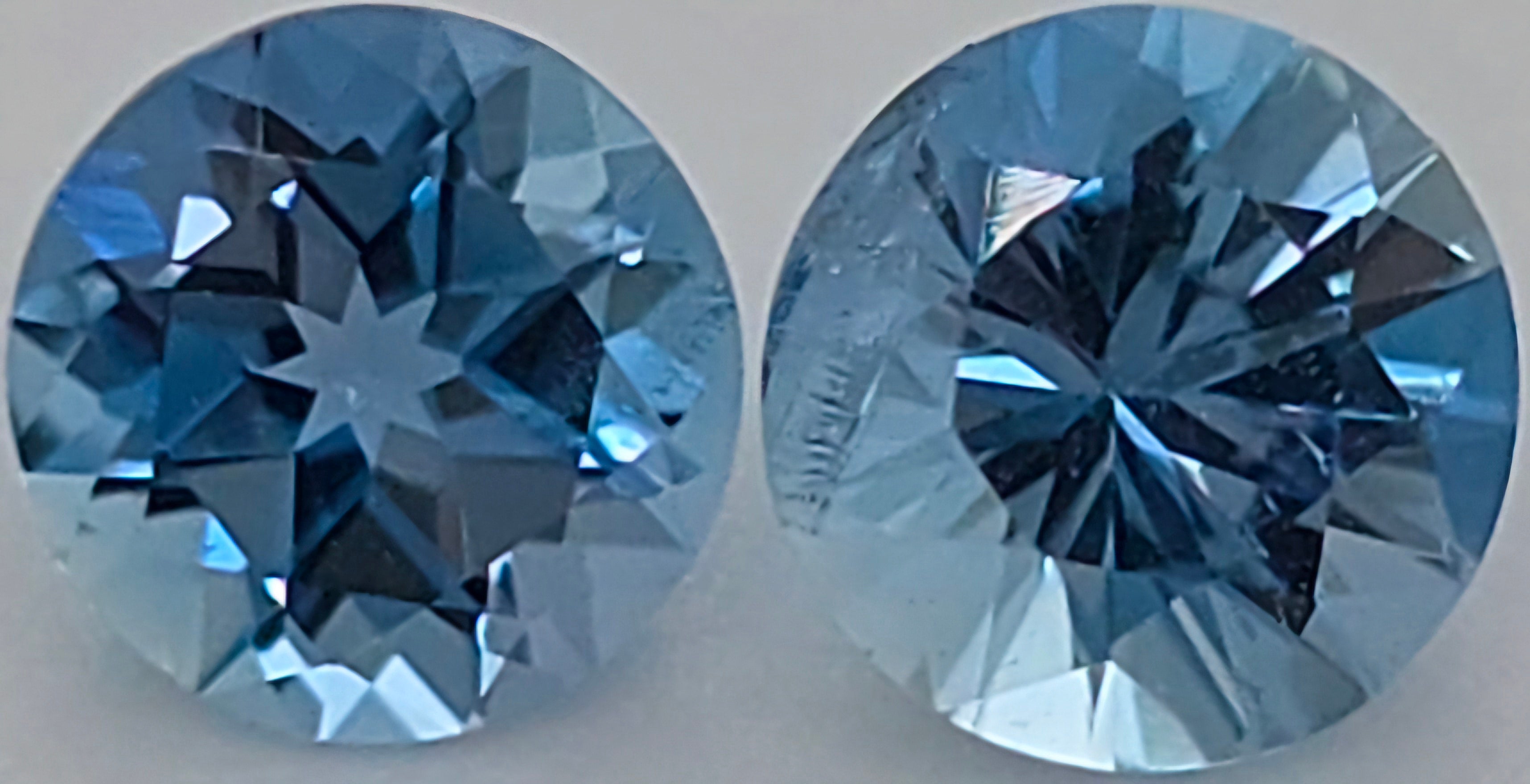Two round brilliant-cut blue gemstones shown side by side on a plain light background.