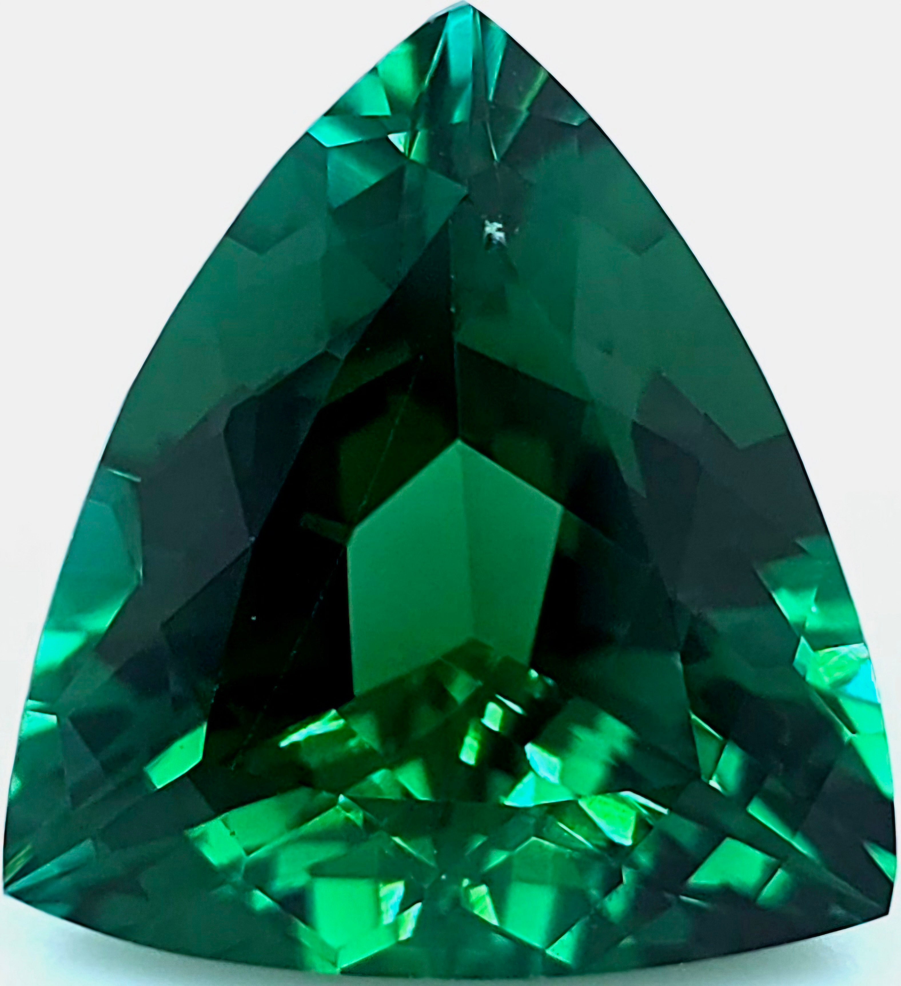 A faceted triangular green gemstone on a white background.