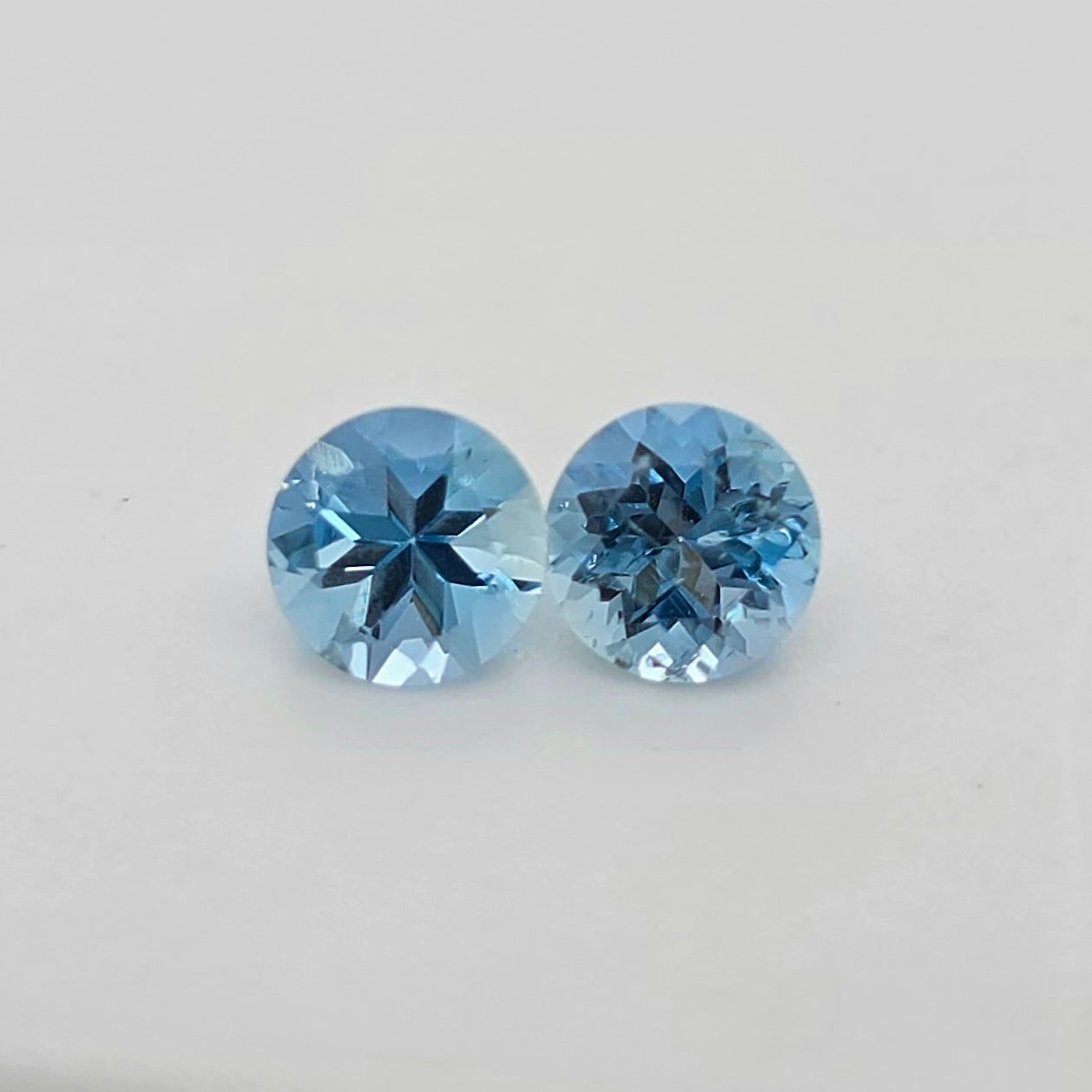 Two round blue gemstones displayed side-by-side on a plain light gray background.