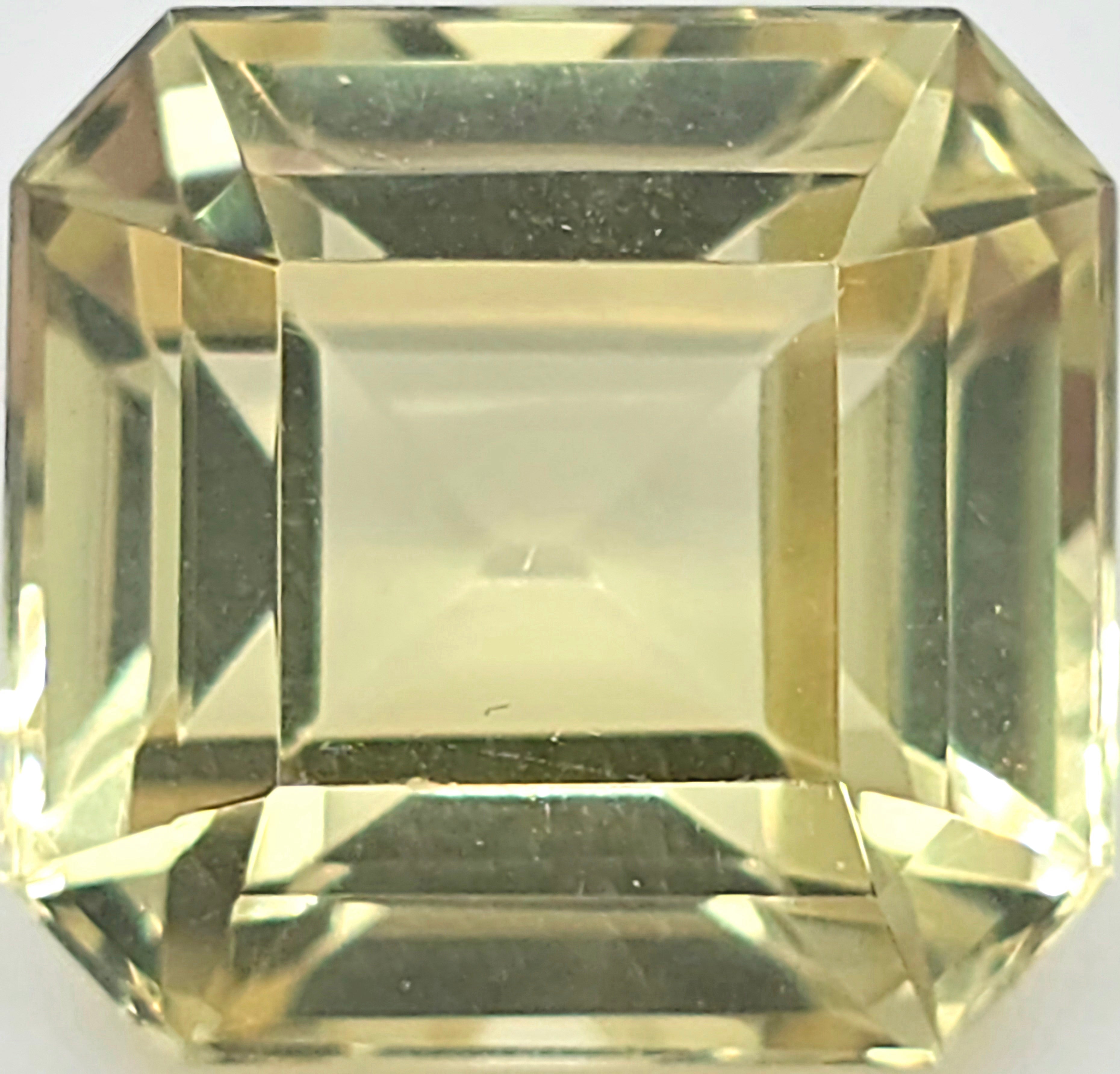 A square emerald-cut yellow gemstone with a faceted, reflective surface, shown against a white background.