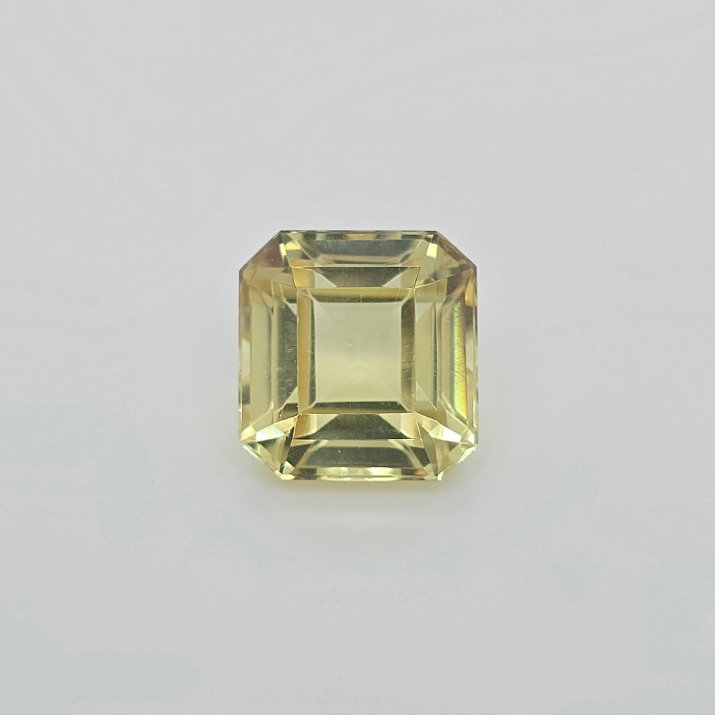 A single square emerald-cut yellow gemstone with faceted edges, centered on a light gray background.