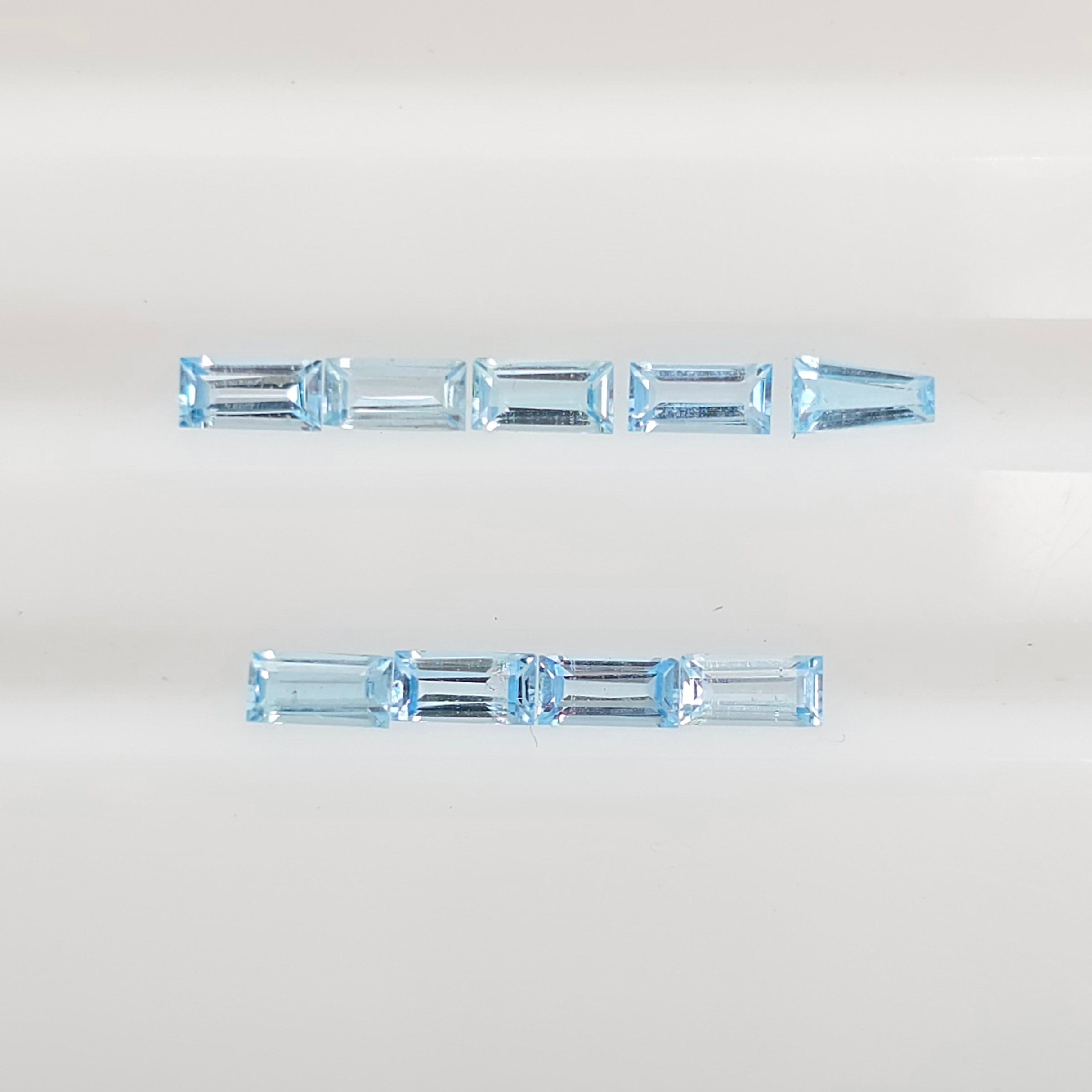 Nine baguette cut gemstones arranged in two horizontal rows on a plain white background