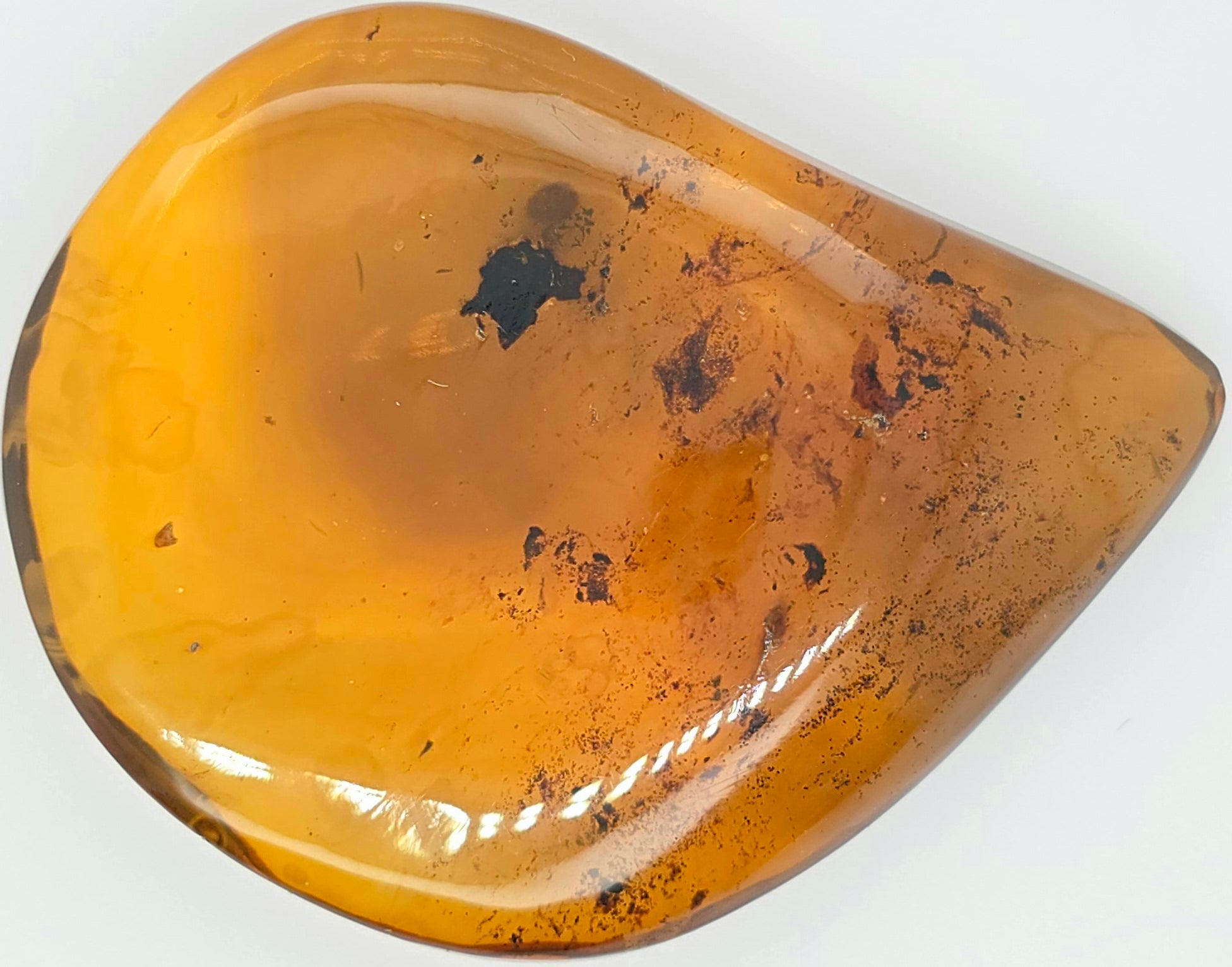 A polished teardrop-shaped amber stone with natural inclusions and dark inclusions, shown on a plain white background.