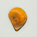 A polished teardrop-shaped amber stone with natural inclusions, displayed on a clean, light off-white background.