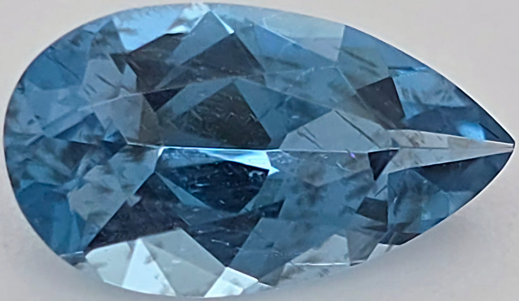 A faceted pear-shaped blue gemstone, shown in close-up on a plain light background.