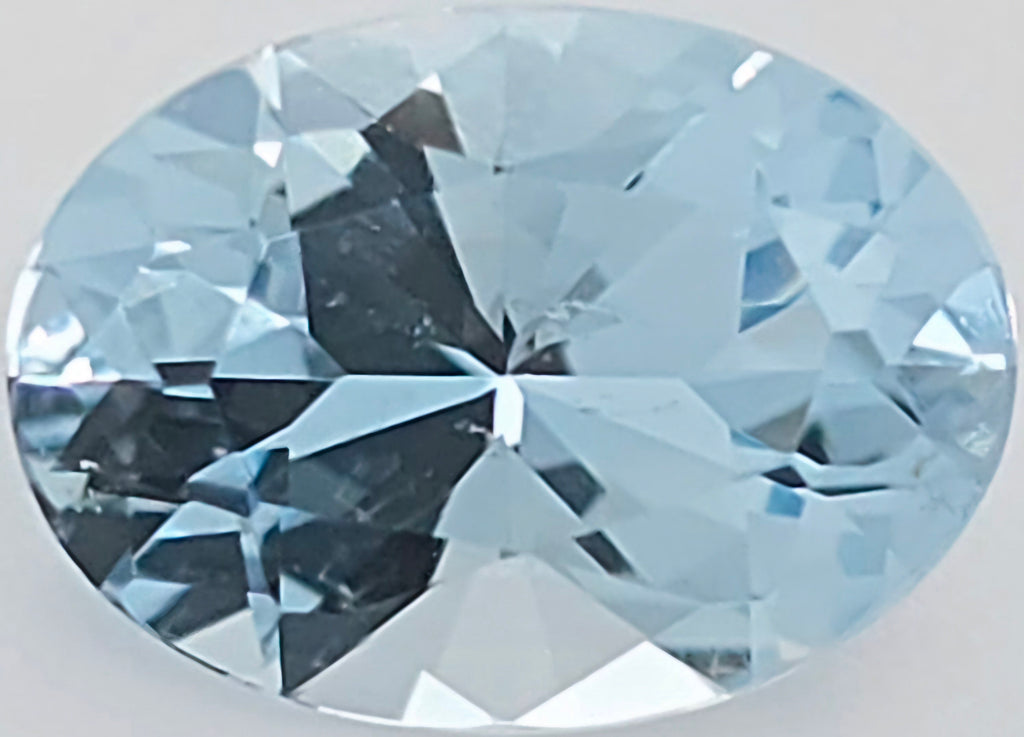 An oval-cut light blue gemstone shown against a plain light gray background.