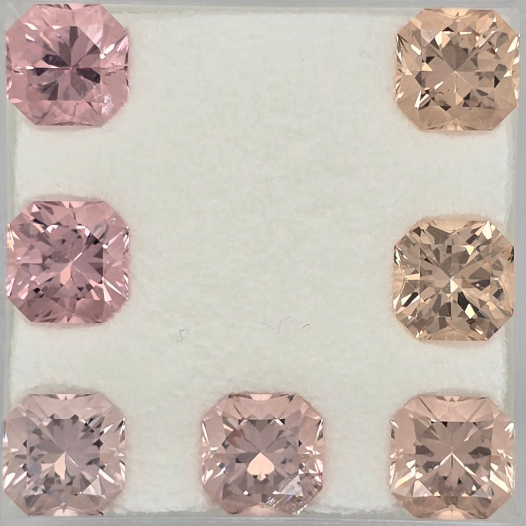 Seven faceted square-cut gemstones arranged in a U-shape on a white textured background. Four stones are light pink, and three are peachy pink with warm golden-brown undertones.