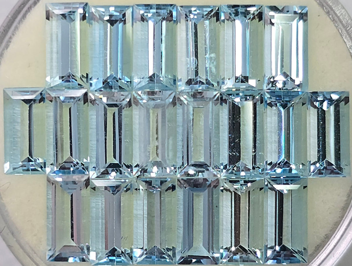 Twenty rectangle light blue faceted stones arranged in three rows on an off-white circular pad 