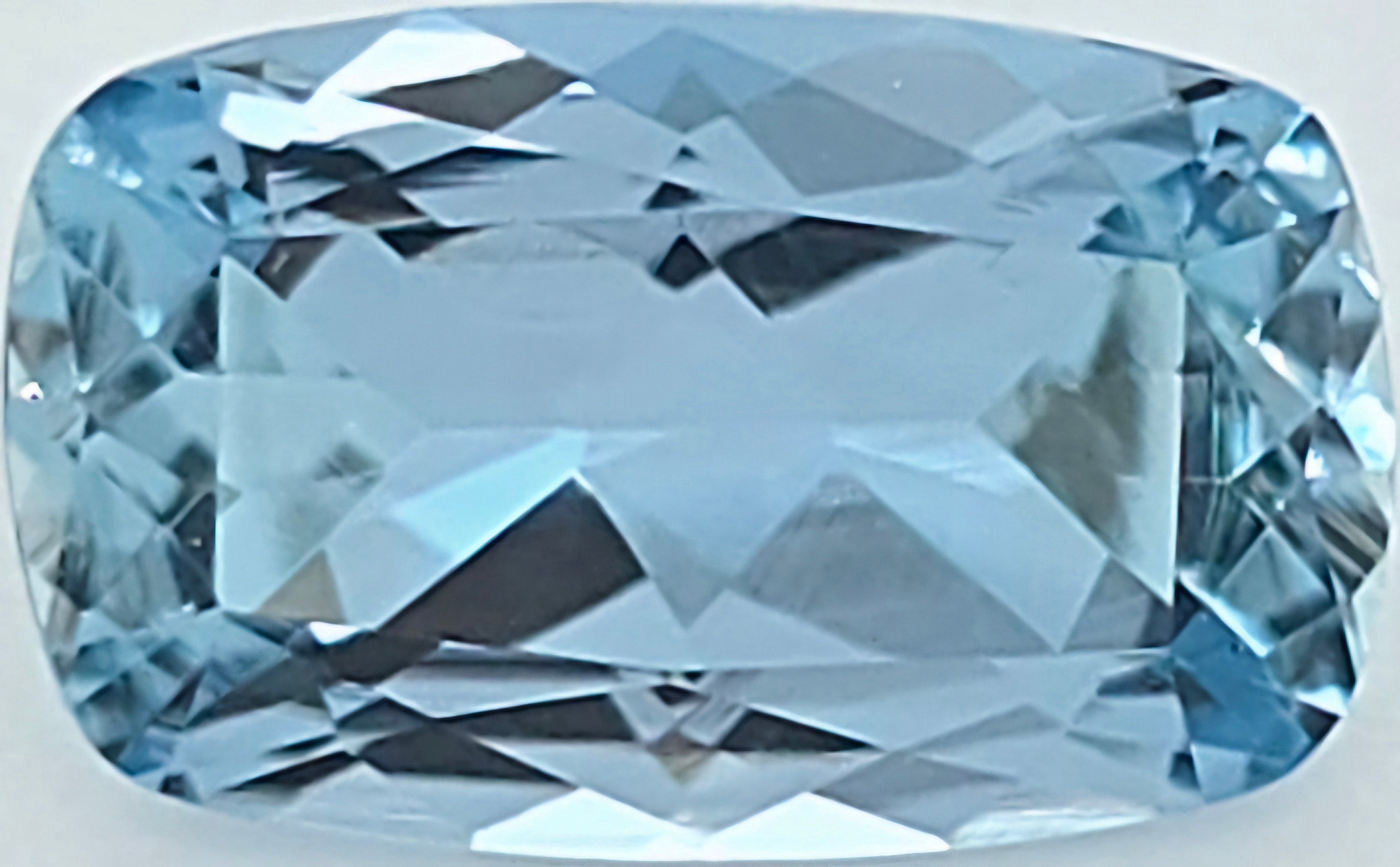 A cushion-cut light blue gemstone with a faceted, geometric pattern, shown on a plain white background.