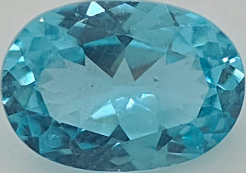 A faceted oval-cut greenish blue gemstone shown against a plain light gray background.