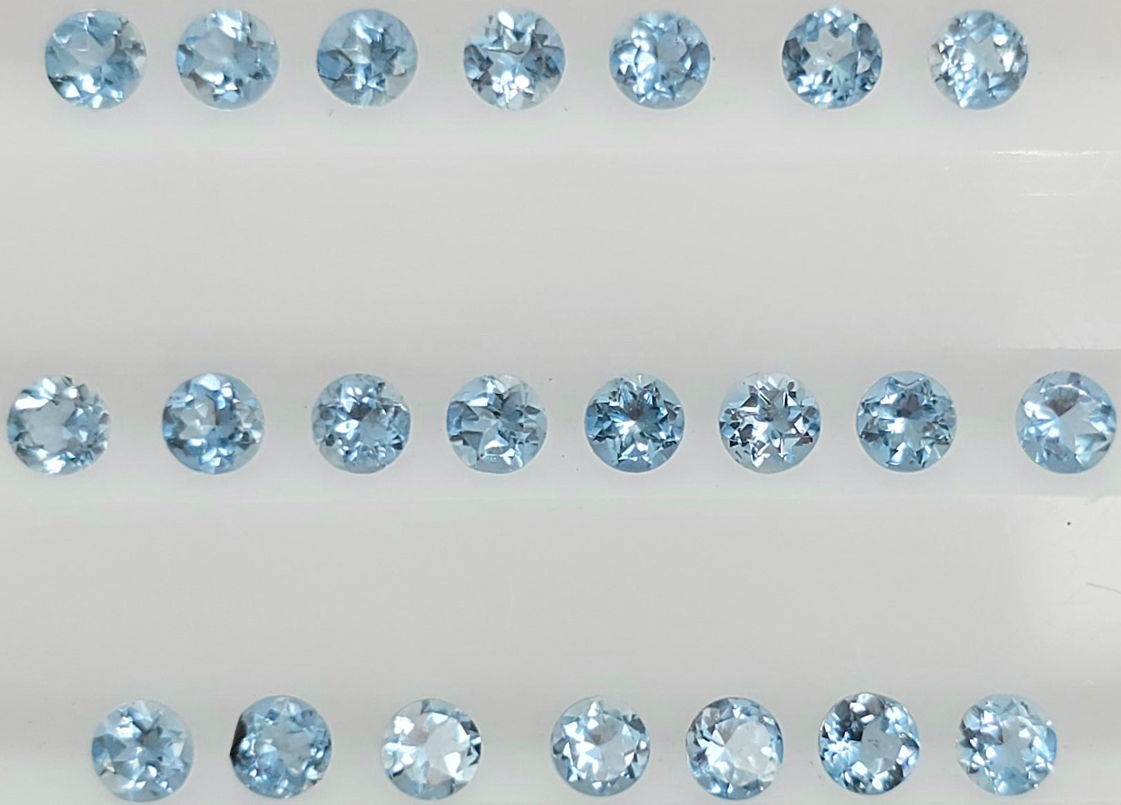 22 round-cut light blue gemstones arranged in three horizontal rows on a plain white background.