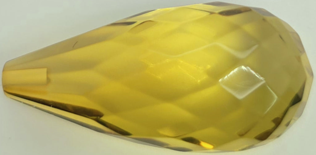A faceted, teardrop-shaped transparent greenish yellow briolette on a plain white background.