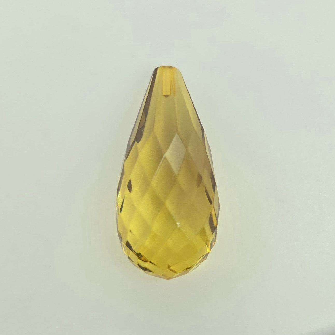 A faceted teardrop-shaped crystal briolette in a transparent greenish-yellow color, shown on a plain light gray background.