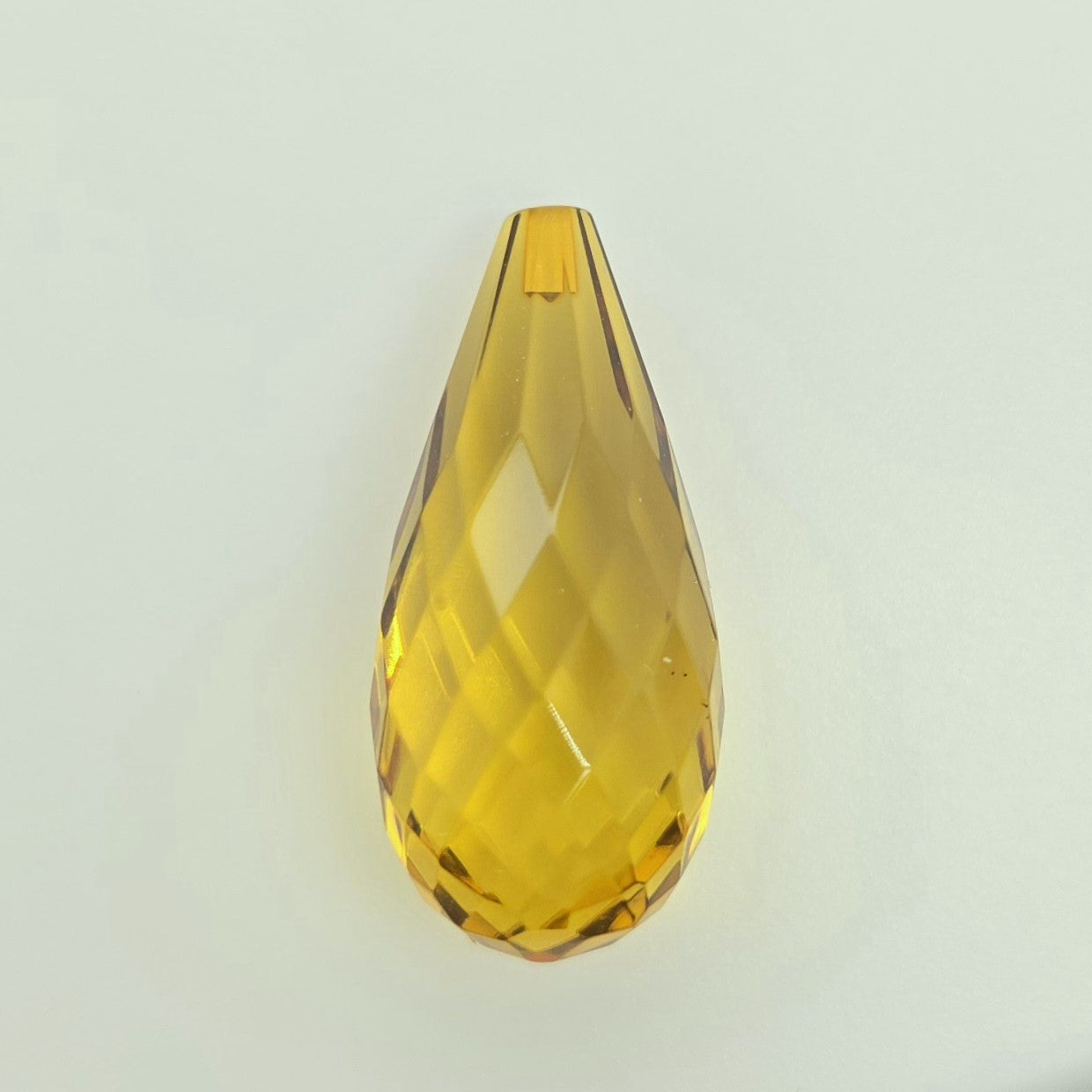 A faceted teardrop-shaped translucent greenish yellow briolette, shown on a plain light gray background.