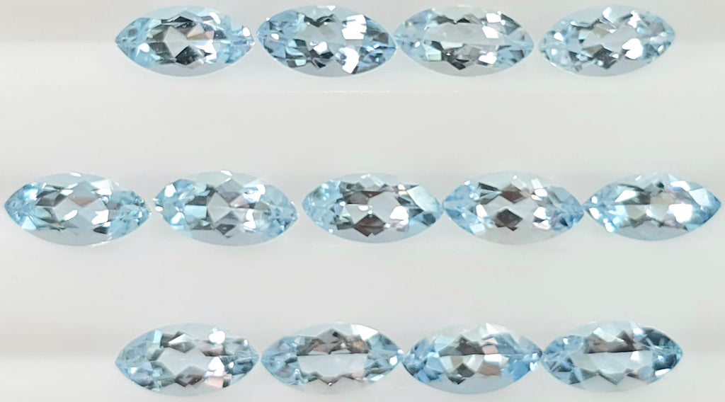 Thirteen light blue marquise-cut gemstones arranged in three rows on a plain white background.