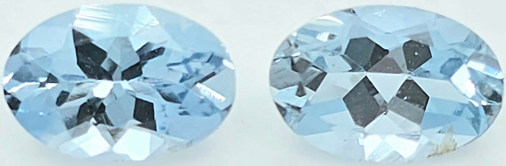 Two oval-cut light blue gemstones shown side by side on a plain white background.
