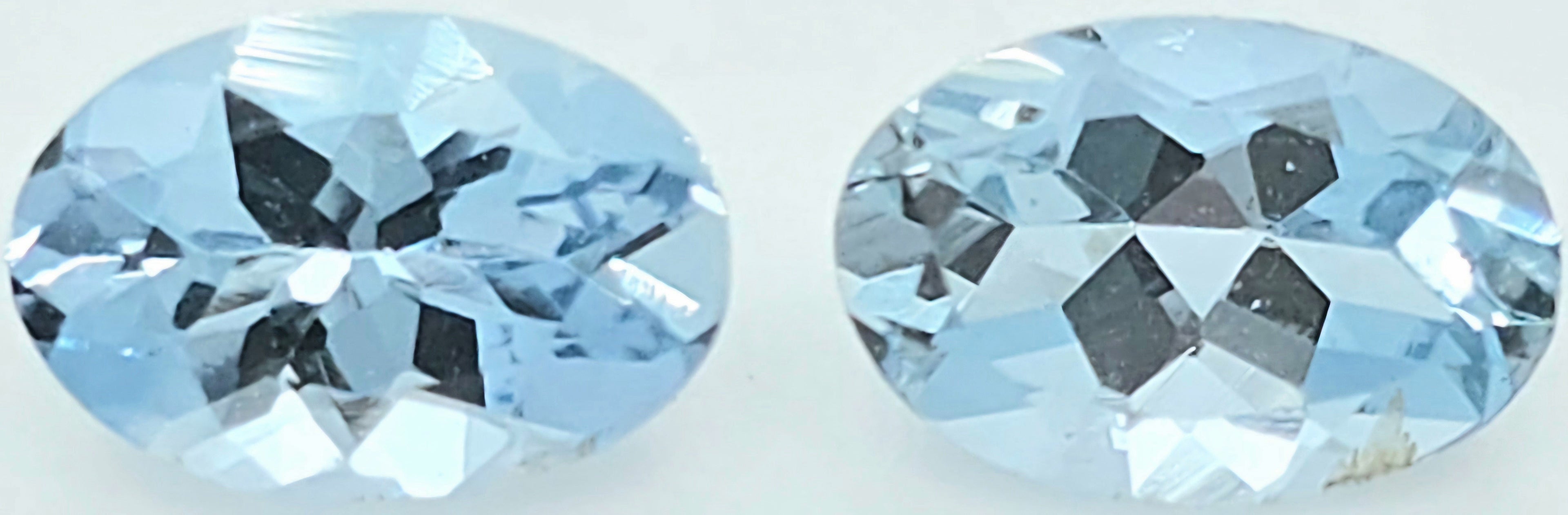 Two oval-cut light blue gemstones shown side by side on a plain white background.