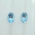 Two oval-cut light blue faceted gemstones displayed side by side on a plain white background.