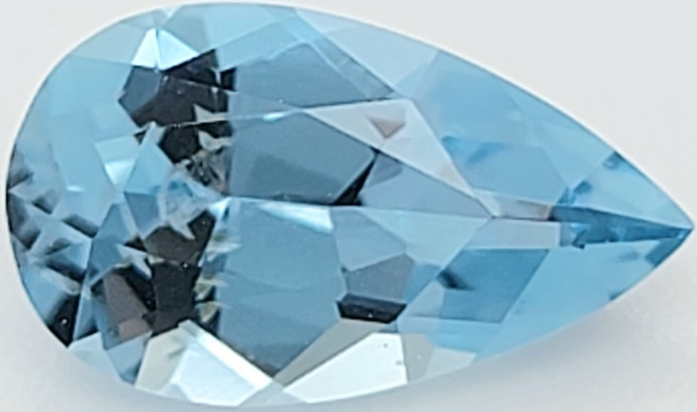 A faceted pear-cut light blue gemstone, shown in close-up on a plain light background.