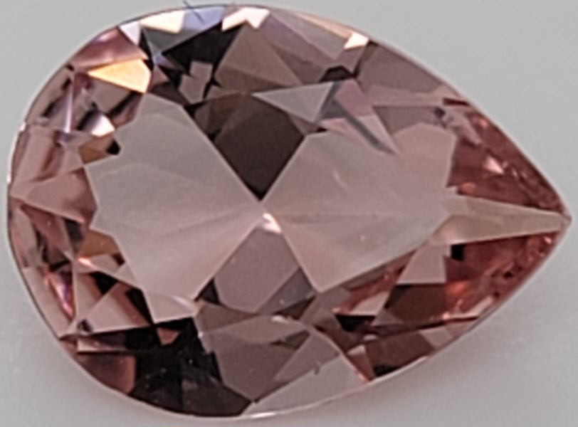 Close up of a transparent pink gemstone on a white to light gray background