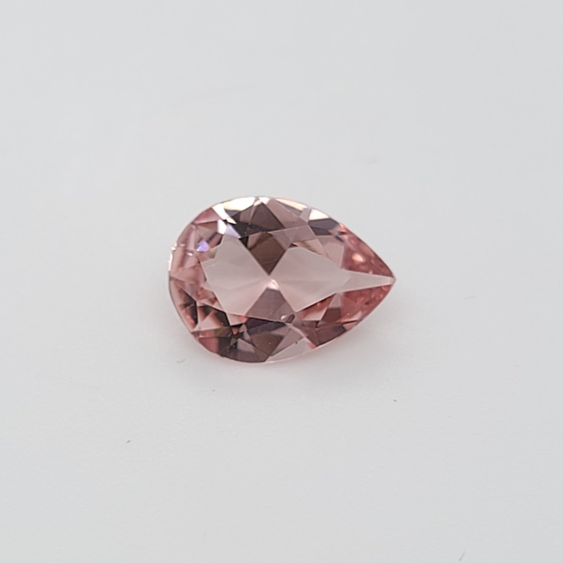 Transparent pink pear shaped gemstone on a white background