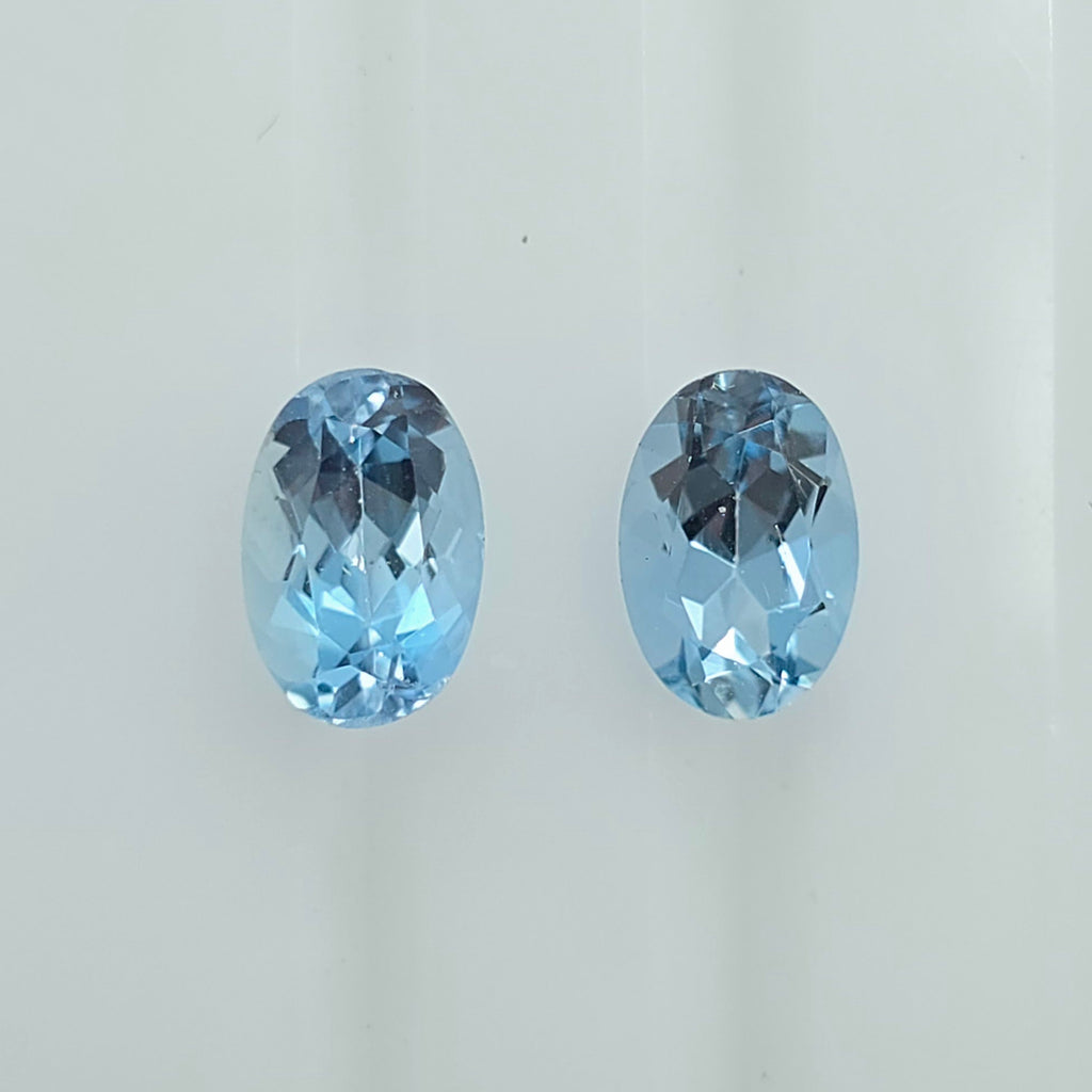 Two oval-cut light blue gemstones displayed side by side on a plain light background.