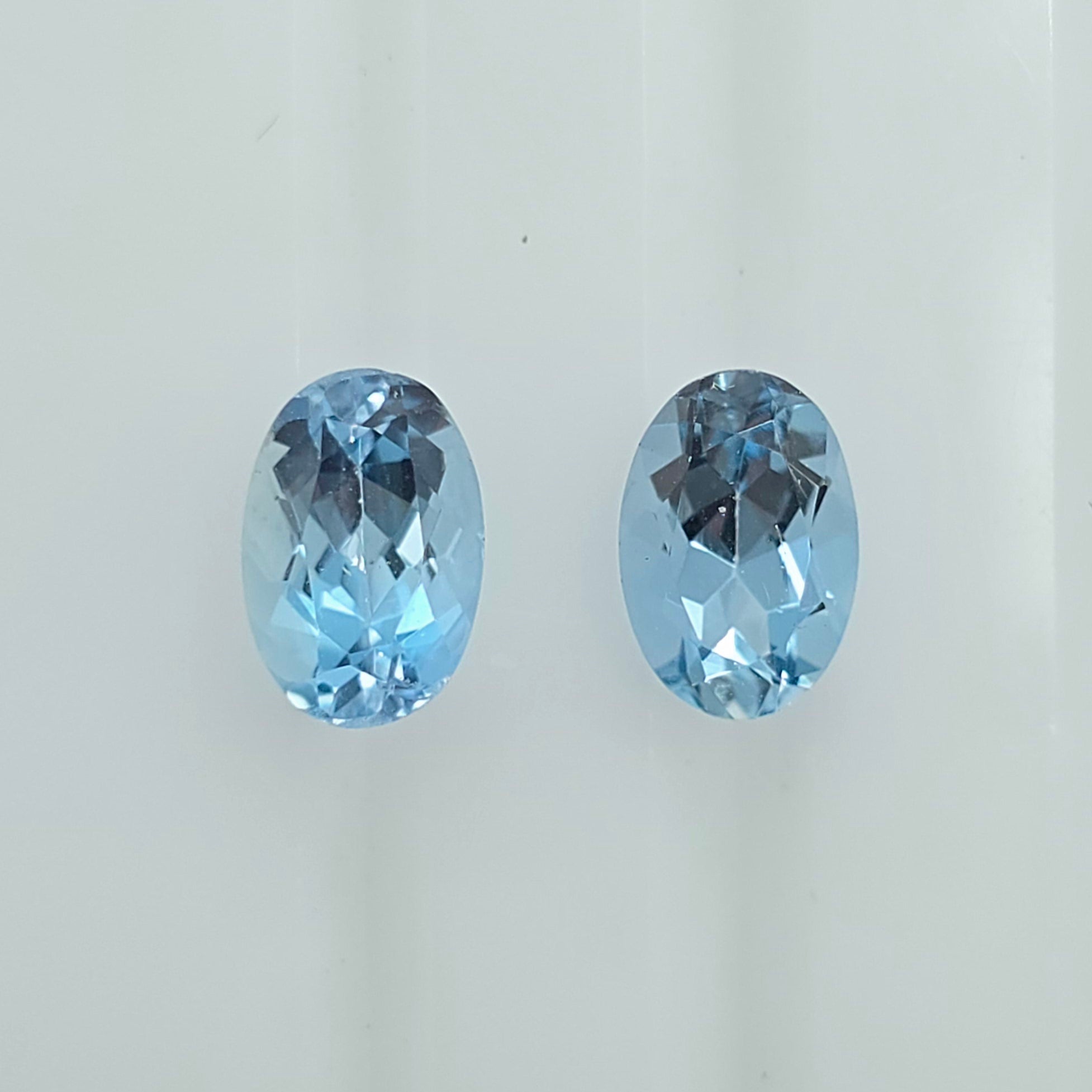 Two oval-cut light blue gemstones displayed side by side on a plain light background.