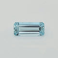 A rectangular emerald-cut light blue gemstone, centered on a clean, light gray background.