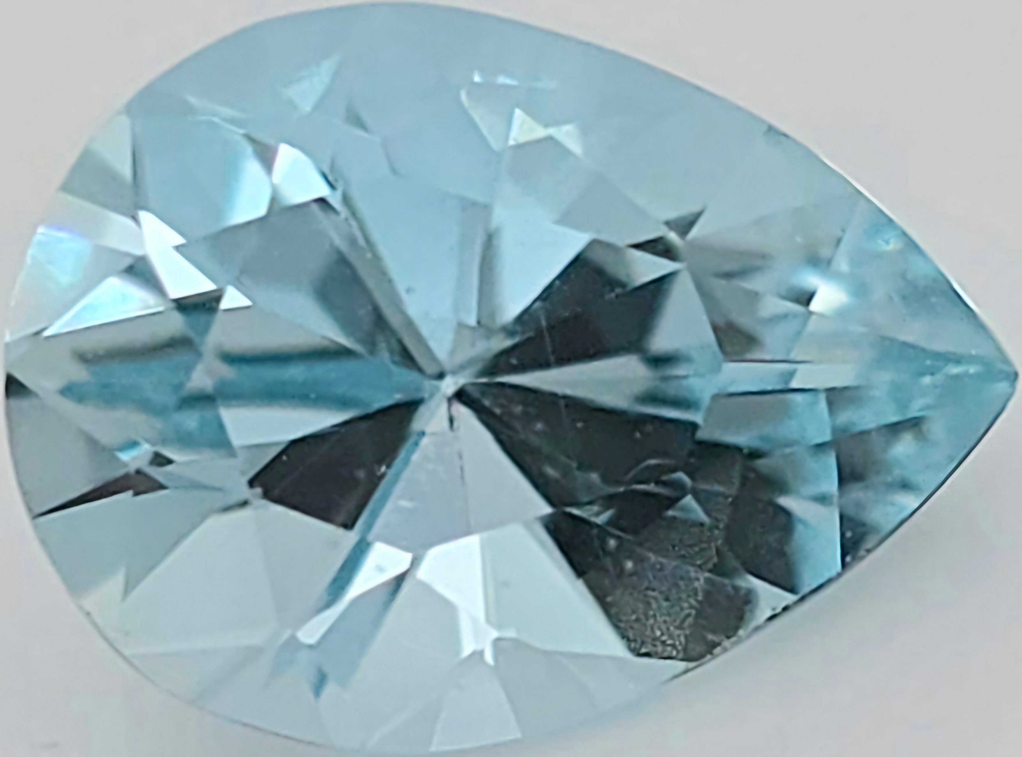 A faceted pear-cut light blue gemstone, shown in close-up on a plain light background.