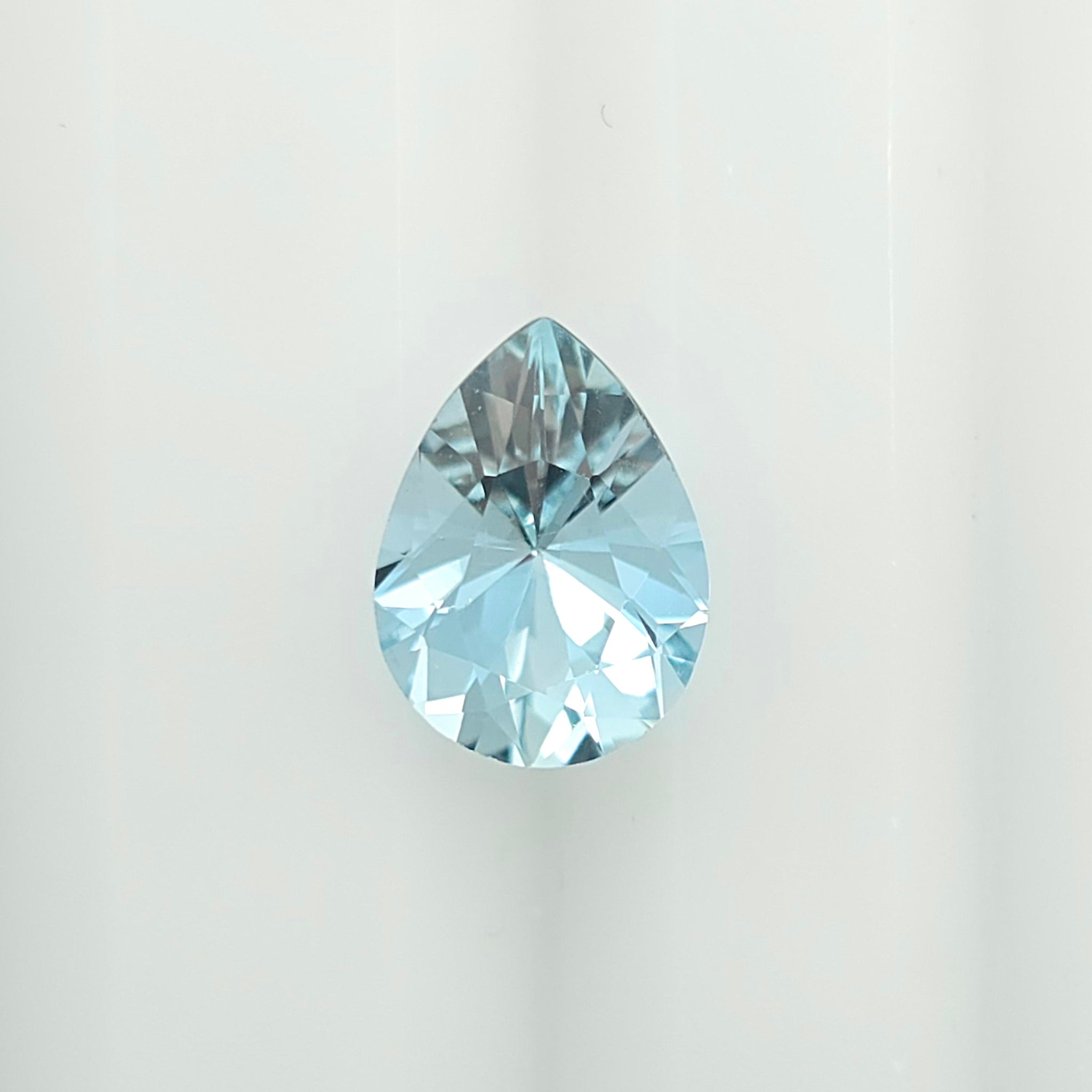 A single faceted teardrop-shaped light blue gemstone centered on a plain white background.