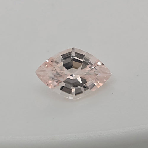 A single lozenge cut pink gemstone with a faceted, reflective surface, centered on a plain light gray background.