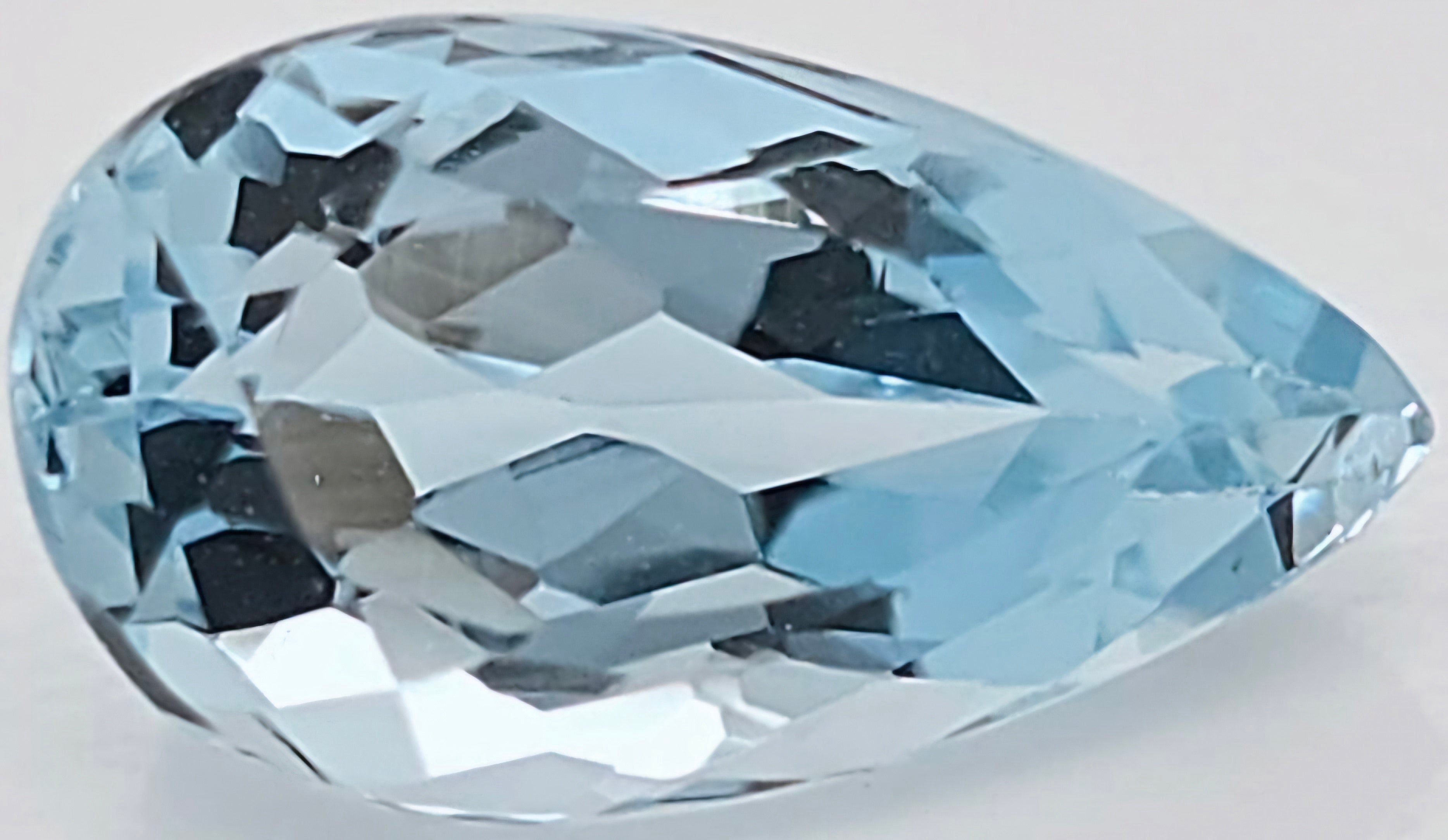 A faceted pear-cut light blue gemstone, shown on a plain light gray background.