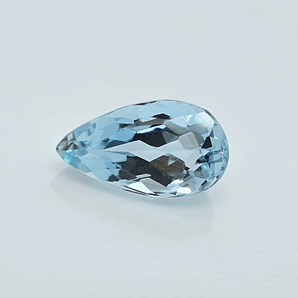 A single pear-shaped light blue gemstone with a faceted cut, displayed on a clean, light gray background.