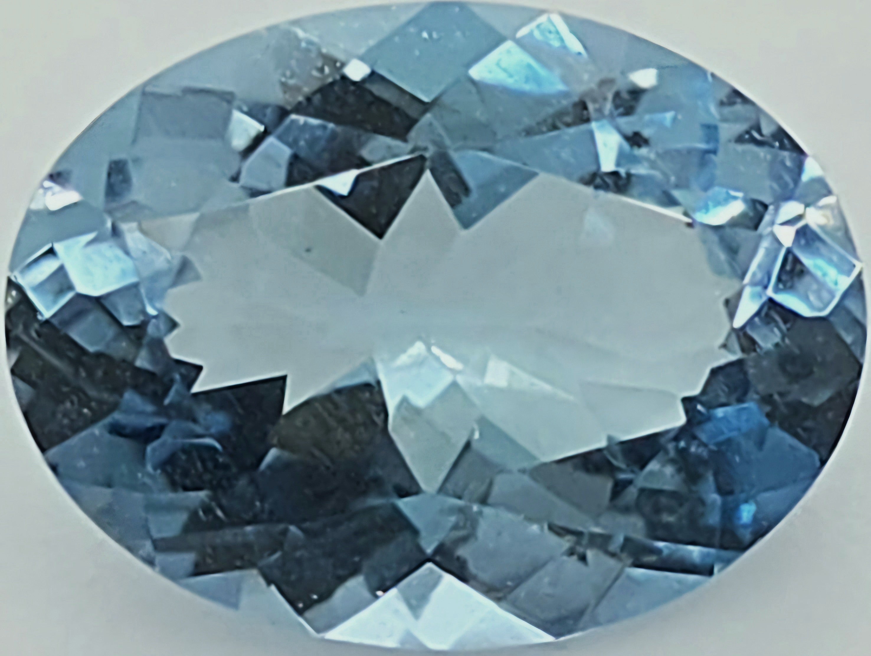 An oval-cut light blue gemstone with a brilliant faceted cut, shown against a plain light gray background.