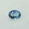 An oval-cut light blue gemstone with faceted cuts, centered on a plain light gray background.