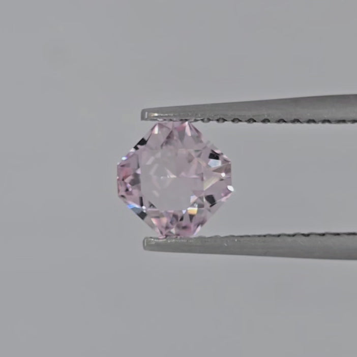 Video of a square pink gemstone in tweezers against a white to gray background